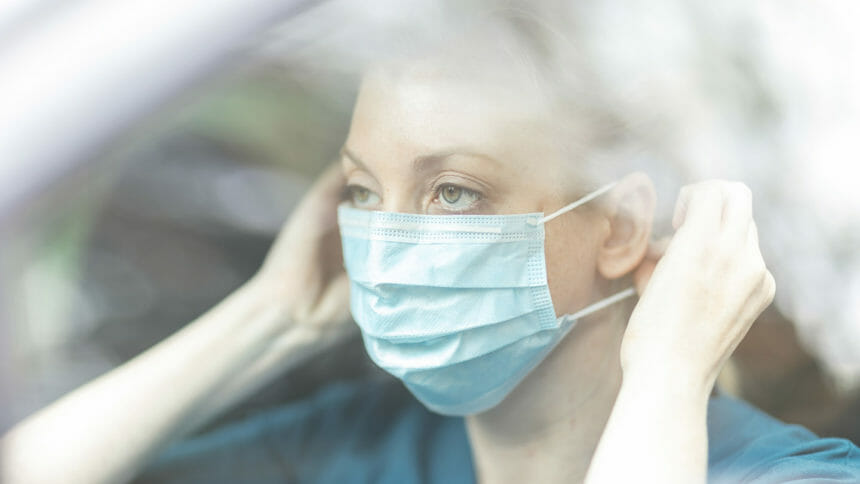 Female community nurse putting on protective mask in car