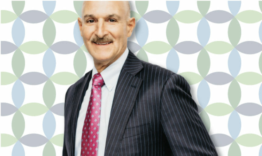 John Capasso wearing a suit in front of blue and green background
