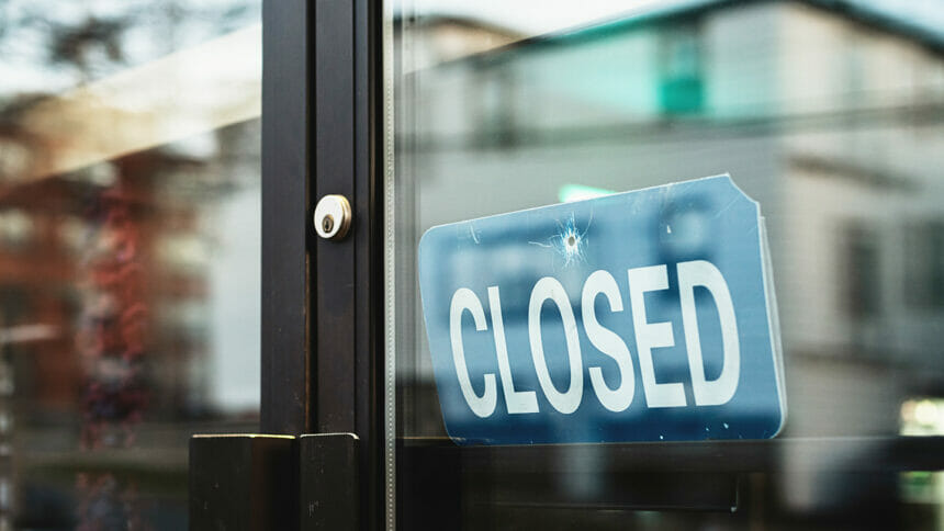 A blue closed sign shows through a glass door